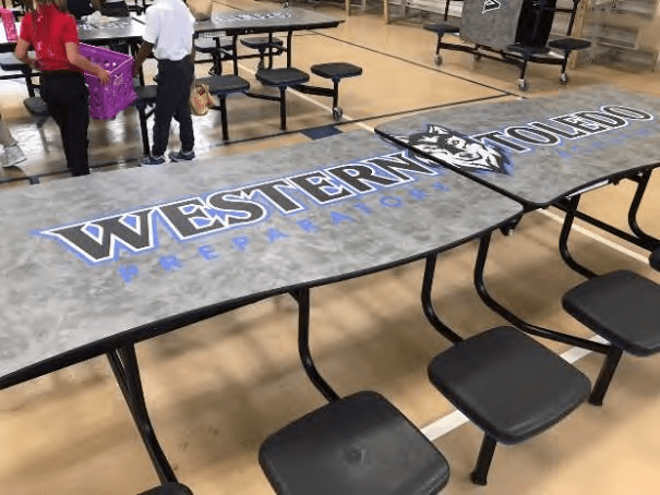 Cafeteria tables with school logo and text.