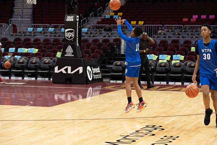 Child in blue uniform shooting a basketball on a court.