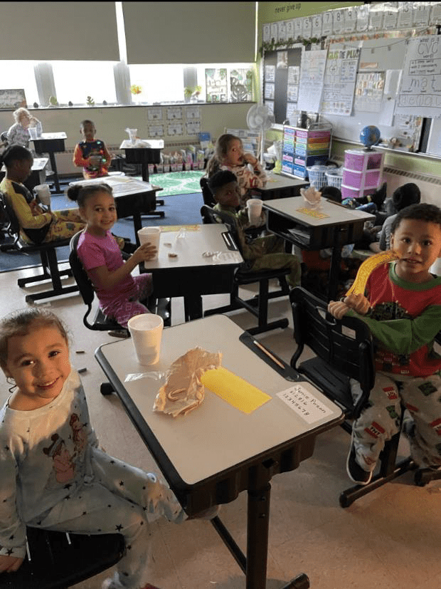 Children in a classroom, some smiling at the camera.