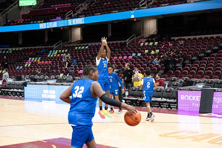 Children in blue jerseys playing basketball in an arena.