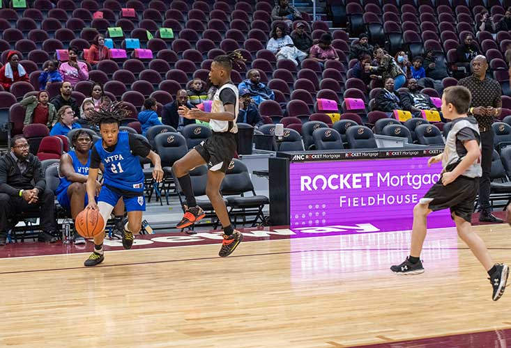 Children playing basketball on a court with spectators.