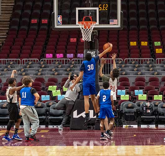 Children playing basketball on a court with an adult photographer.