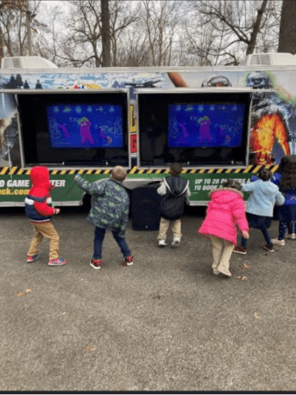 Children playing video games on outdoor screens.