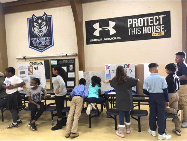 Children presenting school projects at tables.