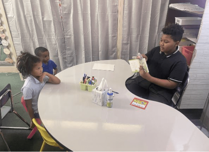 Three children reading together at a table.