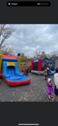 Children and adults near colorful inflatable slides and bounce houses outdoors.