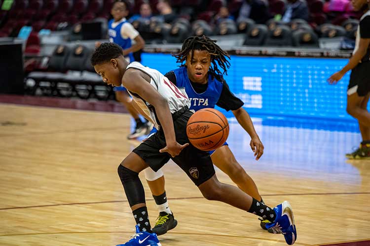 Two young basketball players compete for the ball on a court.