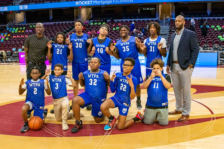 Youth basketball team with two adults and nine children posing on court.