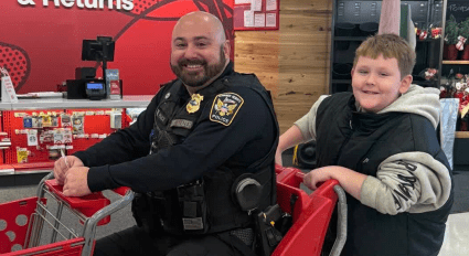 Adult in police uniform and child smiling in a shopping cart.