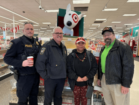 Four adults, two in police uniforms, pose in a store.