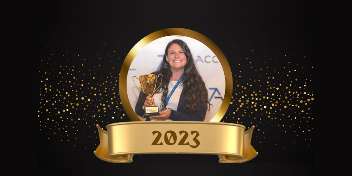 Smiling adult holding a golden trophy with a "2023" banner.